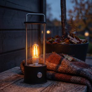 Ledlampe 31 cm i sort med varmt lys på utebord i høstlig kveldsstemning