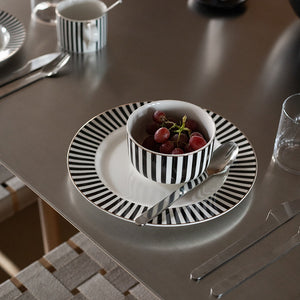 Nova Abby tallerken med svart-stripet design og gullkant, servert med en bolle med druer, på et stilrent middagsbord.