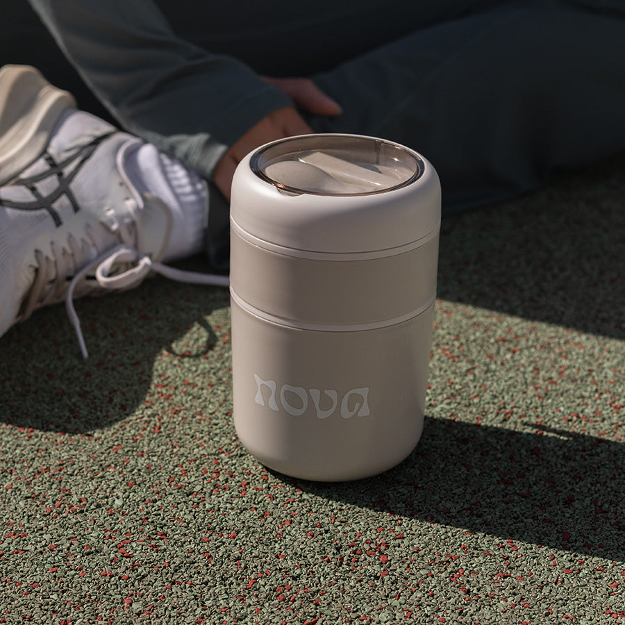 Nova mattermos plassert på bakken, med en sporty bakgrunn, perfekt for å ta med på turer.