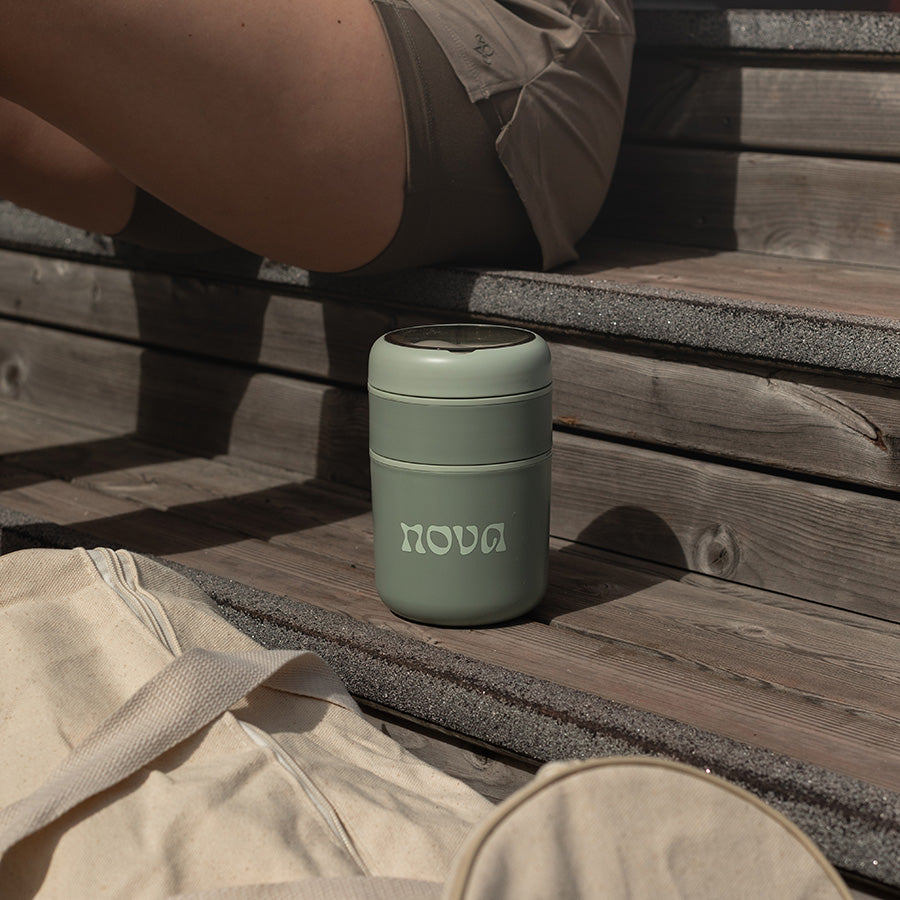 Grønn NOVA mattermos plassert på tretrapper, perfekt for utendørs aktiviteter med stilrent design.