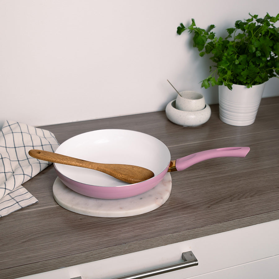 Kokk bruker rosa stekepanne til å steke ingredienser, perfekt for familiemåltider.