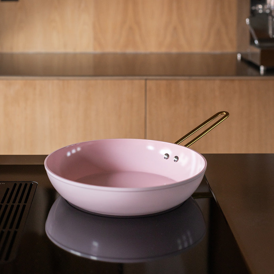 Nova Faye stekepanne i rosa med gullhåndtak på en moderne kjøkkenbenk, ideell for daglig matlaging.