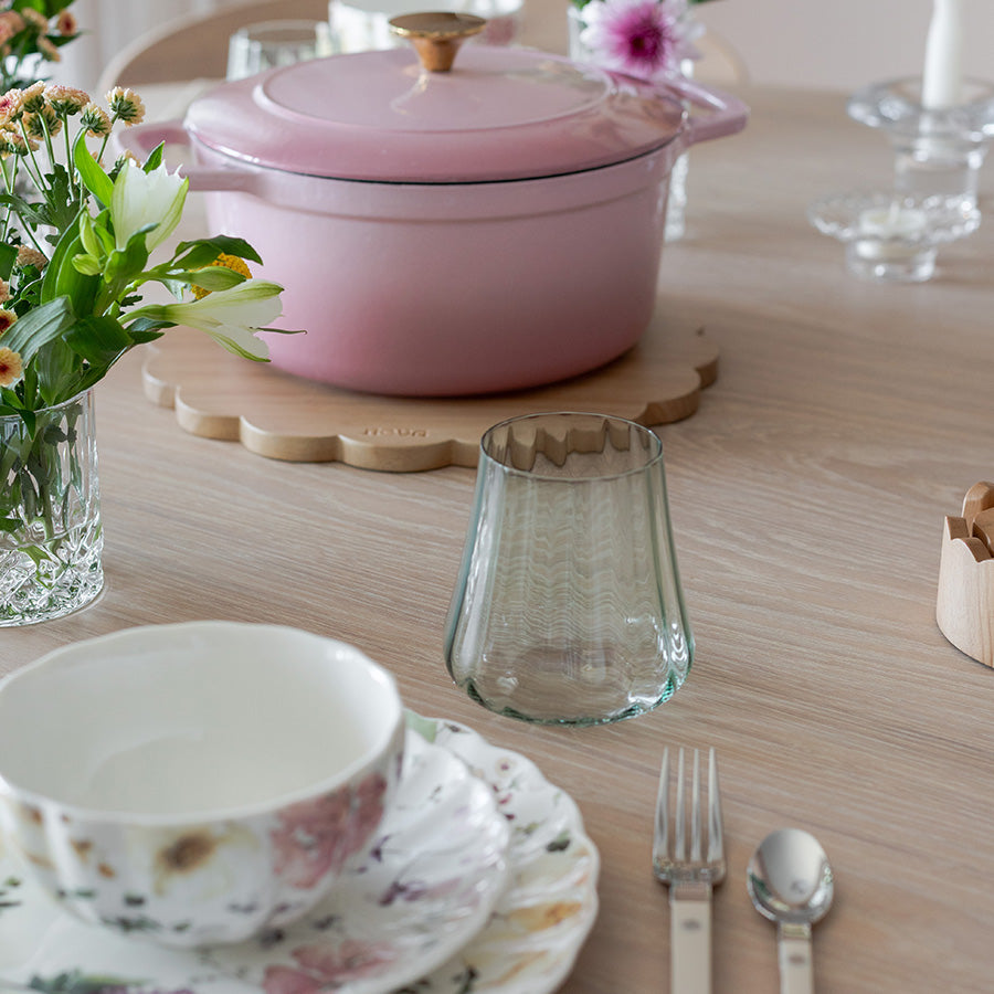 Et vakkert dekket bord med Nova Lottie vannglass i grønt, sammen med en rosa gryte og blomster, som skaper en koselig spiseopplevelse.