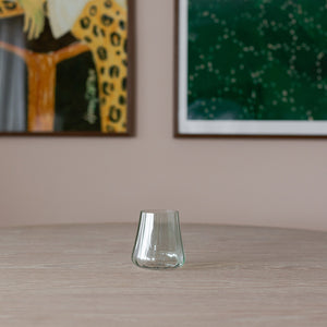 Nærbilde av et enkelt Nova Lottie vannglass i grønt plassert på et bord, med kunstverk i bakgrunnen som gir en stilren atmosfære.