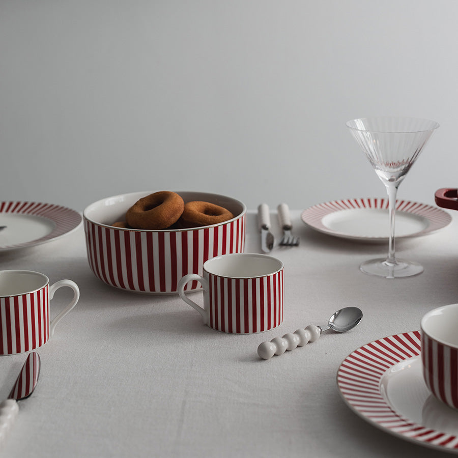 Nærbilde av borddekking med Nova Abby Tallerken 26cm Rød m/Gull dekal - viser serviset med donuts, perfekt for koselige frokoster og samlinger.