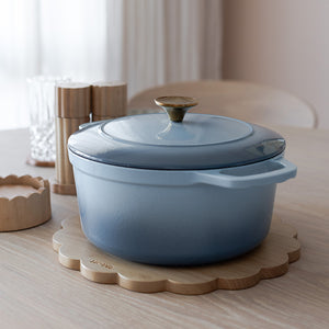 NOVA Dynamic Støpejernsgryte 4,3L 24cm Lyseblå på et bord, klar til bruk i et moderne kjøkkenmiljø.