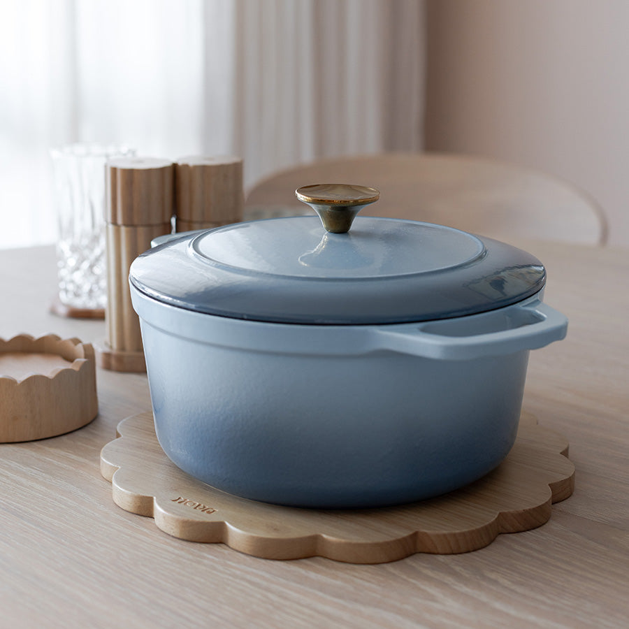 NOVA Dynamic Støpejernsgryte 4,3L 24cm Lyseblå på et bord, klar til bruk i et moderne kjøkkenmiljø.