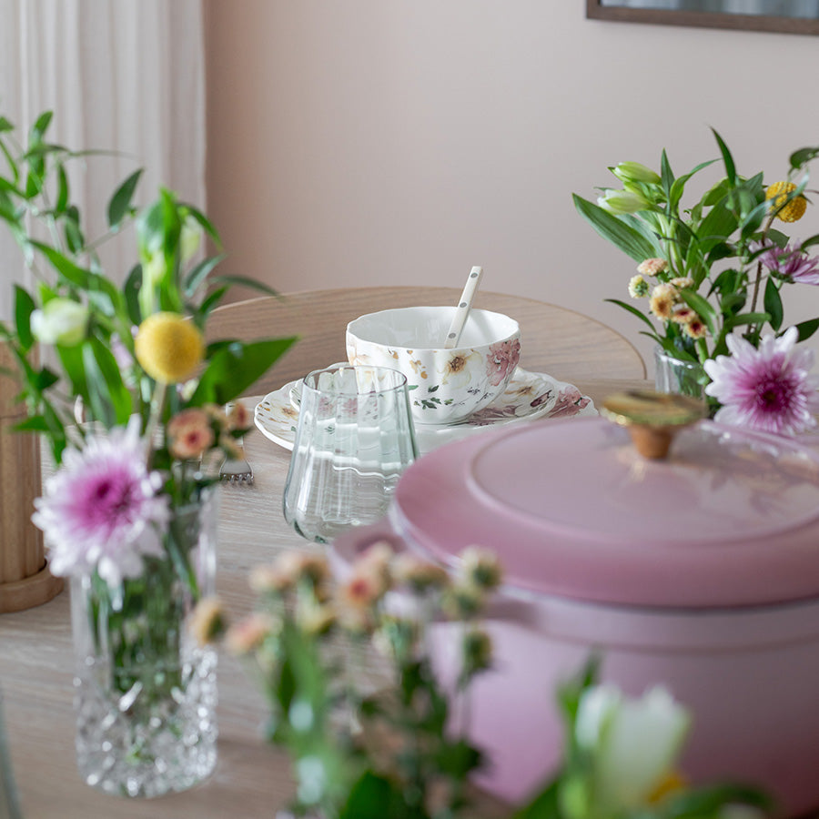 Vakkert dekket bord med Nova Lilly tallerken 26cm Villblomst, blomster i ulike vaser, og en rosa gryte, perfekt for anledninger.