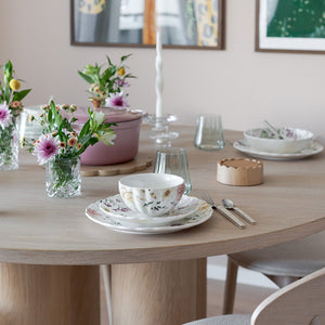 Elegant borddekk med Nova Lilly tallerken 26cm Villblomst, blomsterdekorasjoner, glass og bestikk, perfekt til måltider.