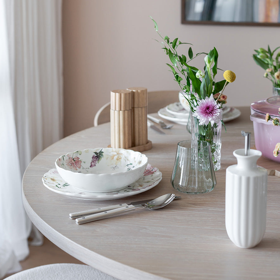 Stylish Nova Lilly Olje Dispenser 300ml Hvit plassert på et elegant spisebord med blomster, tallerkener og glass, ideell for oppbevaring av olivenolje og dressinger.