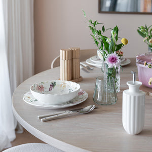 Stylish Nova Lilly Olje Dispenser 300ml Hvit plassert på et elegant spisebord med blomster, tallerkener og glass, ideell for oppbevaring av olivenolje og dressinger.