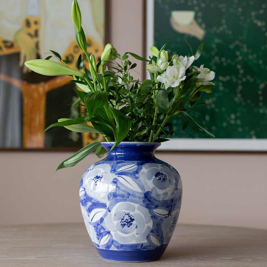 Nova Poppy Vase Keramikk 25cm Blå med hvite blomster - Vasen på et bord, dekorert med friske stilker og gir et elegant preg.