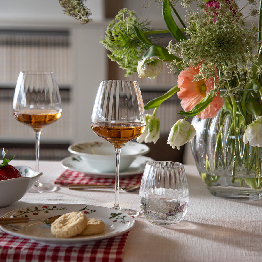 Hadeland Glassverk Odysse vannglass med optikkmønster fylt med vann på elegant dekket bord med blomster