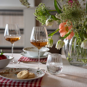 Hadeland Glassverk Odysse vannglass med optikkmønster fylt med vann på elegant dekket bord med blomster