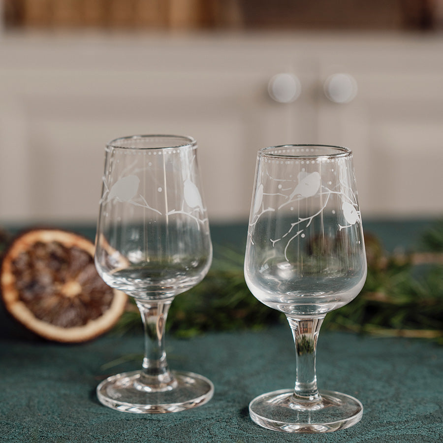 To Porsgrund Dompap snapsglass med gravert fuglemotiv på festdekket bord