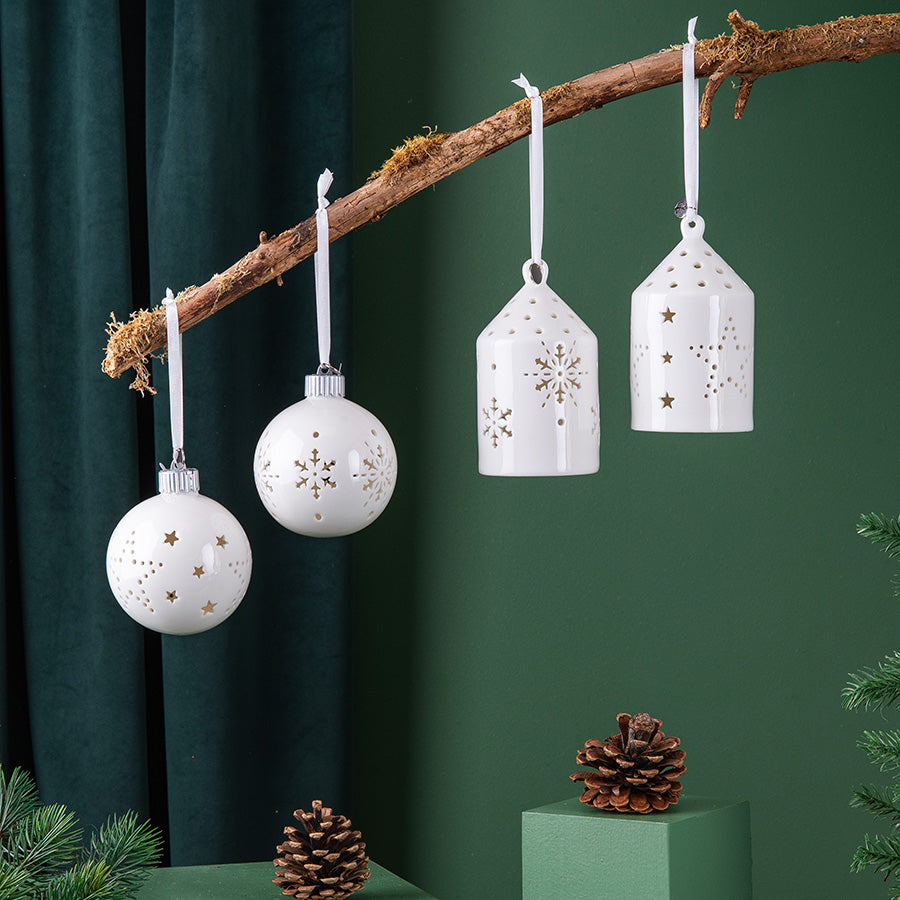 To hvite porselenshus med LED-lys hengt på en gren sammen med julekuler, dekorativt ornament til juletreet