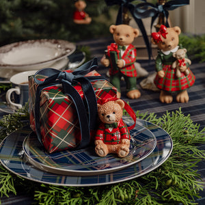 Sjarmerende bjørneornament i rødt og grønt ved en innpakket julegave på festlig julebord