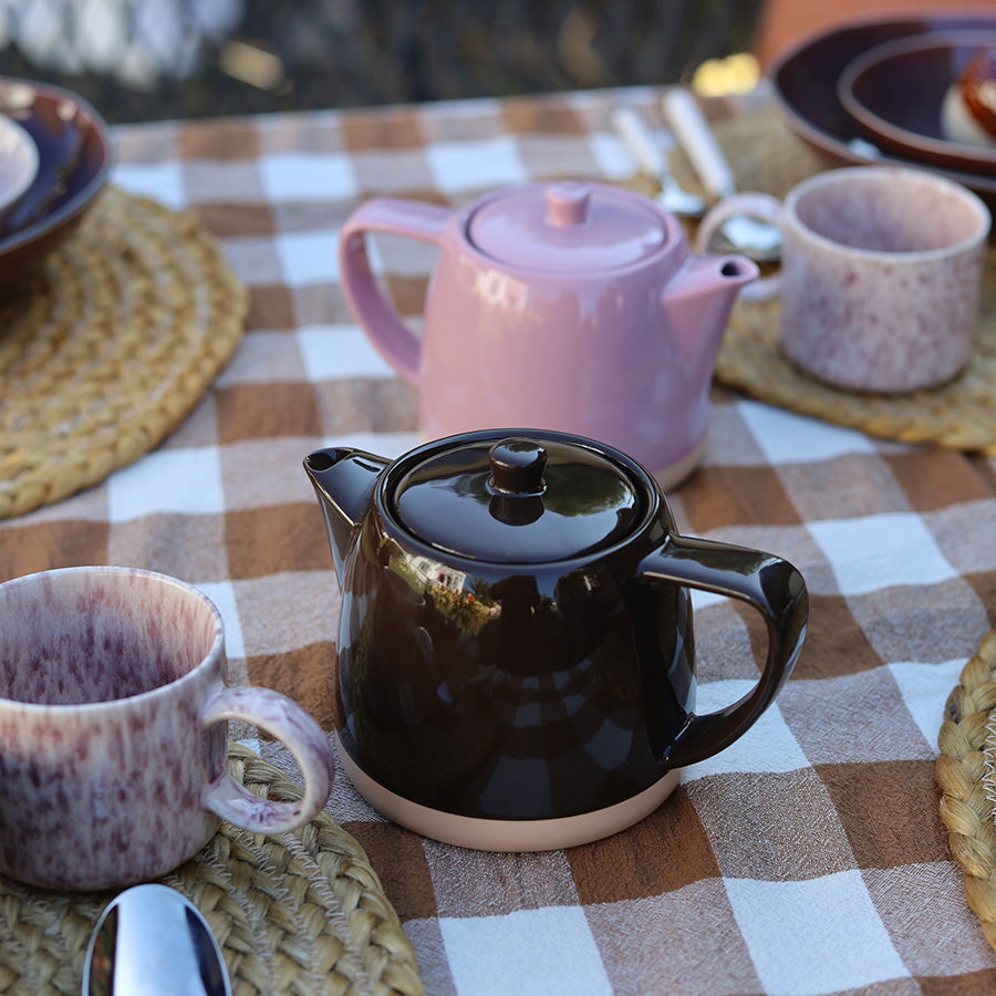 Brun tekanne fra Teatime-serien på dekket bord sammen med kopper og rosa tekanne