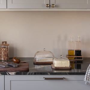 To smørklokker i ribbet glass fra Christiania 1739 Pantry-serien på kjøkkenbenken, som gir en stilfull presentasjon av smør.