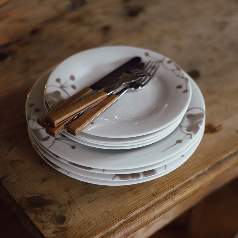 Porsgrund Porselænsfabrik Maxistrå Tallerken 22 cm Beige, tallerkener stablet på en treplate med kniv og gaffel, perfekt for borddekor.