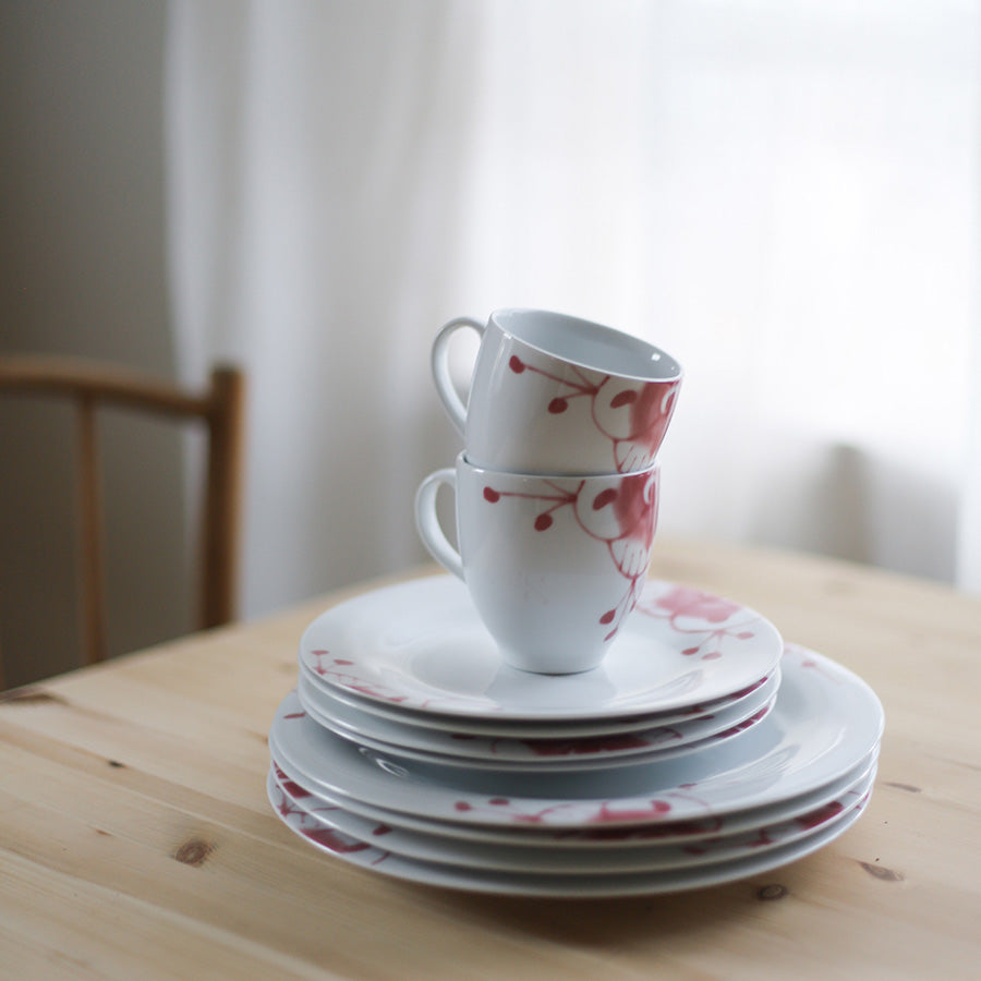 Porsgrund Porselænsfabrik Maxistrå Krus 35cl Nomi Rosa stablet sammen med tallerkener i Maxistrå-serien, på et bord med naturlig trebelegg.