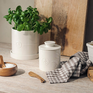 Porsgrund Porselænsfabrik ildfast urtepotte med underskål 14 cm i hvit, plassert på kjøkkenbenken med basilikumplante. Stilren urtepotte for moderne hjem.