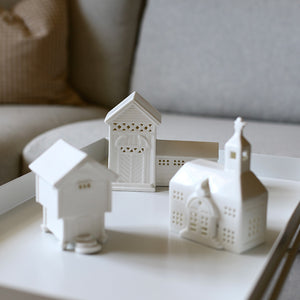 Samling av porselensminiaturehus inkludert Fløyen-bygget på Lysebu, designet av Jette Frölich fra Porsgrunds Porselænsfabrik, plassert på et bord.