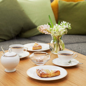 Elegant kaffebord med Porsgrunds Porselænsfabrik Nathalie Gull sukkerskål, te-kopper og bakverk, som viser den vakre designen og bruk av sukker.