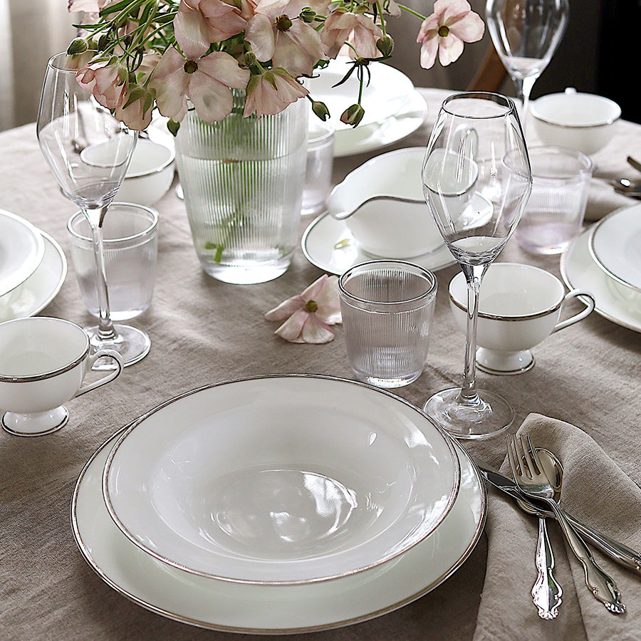 Porsgrunds Porselænsfabrik Nathalie Platinum dekket bord med tekopper, skåler og blomster, perfekt for et elegant middagsselskap.