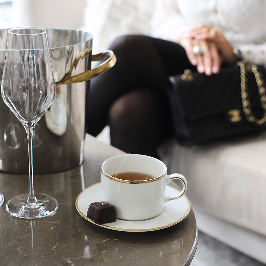 Porsgrund Porselænsfabrik Isabelle Platinum tekopp med skål, servert med en sjokolade på et moderne bord, perfekt for en stilfull teopplevelse.