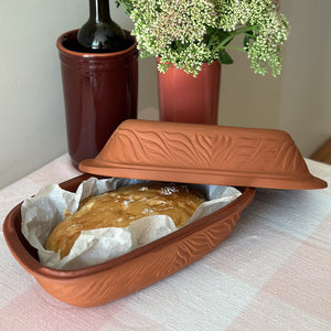Terracotta Leirgryte med nybakt brød, klar til servering fra ovn til bord