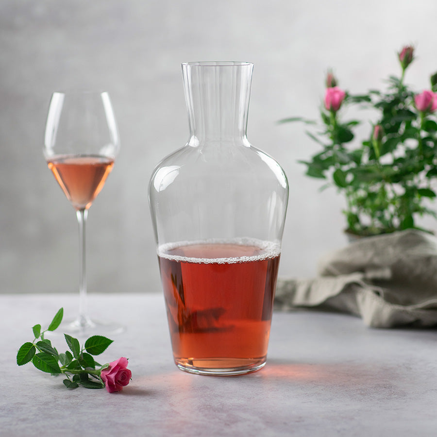 Riedel dekanter med rosévin, plassert på et bord med blomster, ideell for middagsarrangementer.