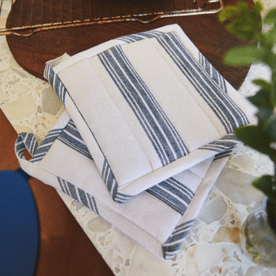 ROSENDAHL Rosendahl Grytekluter 22x22cm 2pk Blå – grytekluter med varmebeskyttende polstring og blå striper, vist på kjøkkenbord