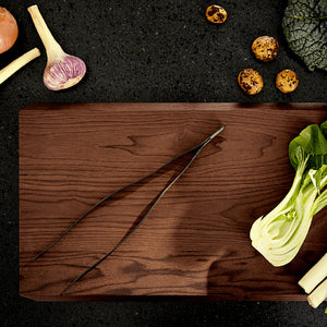 Rosendahl Rå stekepinsett plassert på en vakker treplate med grønnsaker, ideelt for både grilling og plating.