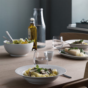 Royal Copenhagen Hvit Riflet Dyptallerken 21cm i en bordsetting med pasta og salat, fremhever den stilige bruken av dyptallerkenen.