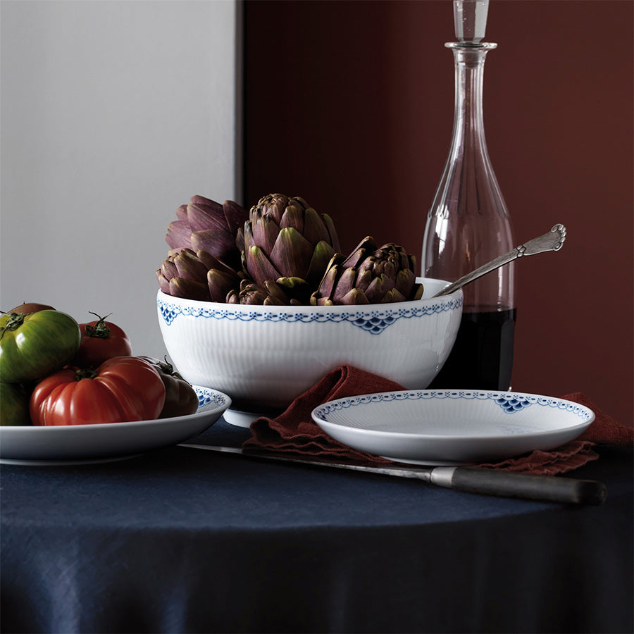 Royal Copenhagen Prinsesse Blå Skål 310cl - Stor skål fylt med ferske artiskokker, omgitt av tomater og rødvin på et elegant bord, perfekt for festlige anledninger.