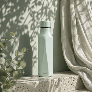 Scanpan termoflaske i eucalyptus, plassert på en lys overflate med naturlige skygger, perfekt for moderne livsstil.