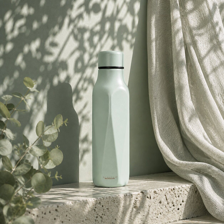 Scanpan termoflaske i eucalyptus, plassert på en lys overflate med naturlige skygger, perfekt for moderne livsstil.