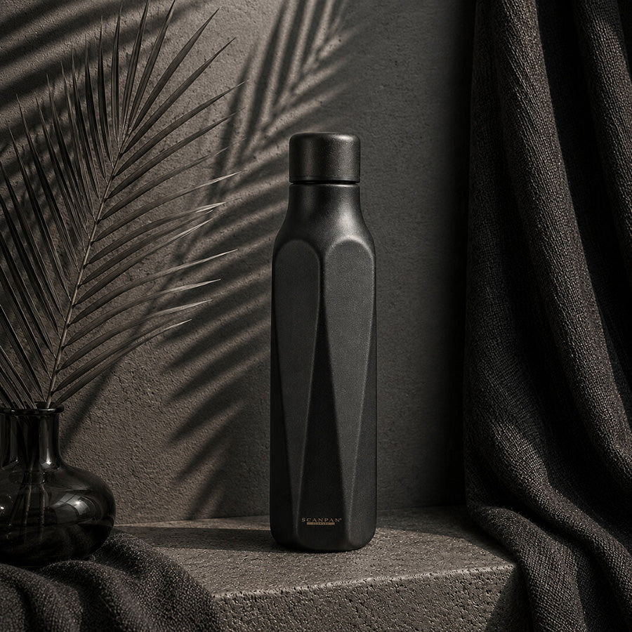 Elegant Scanpan termoflaske i obsidian med en stilren matt overflate, fotografert i et moderne miljø med skygger som fremhever flaskens design. Passer perfekt til hverdagsbruk.
