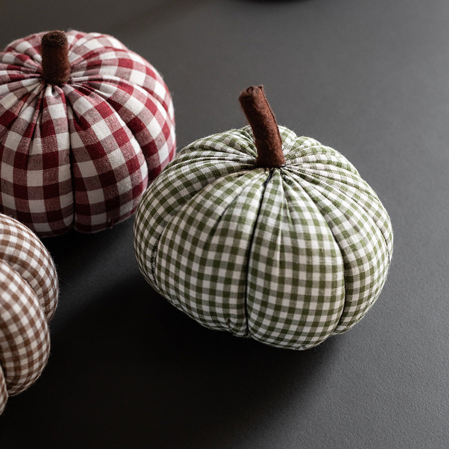 Elegant gresskar i rutete tekstil med grønne og brune toner, perfekt for høstdekorasjon.