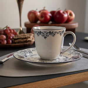 Seasons Fall Collection kopp med hank, blå blomsterprint, elegant plassert på et bord med frukt og kjeks, ideell for kaffe eller te.