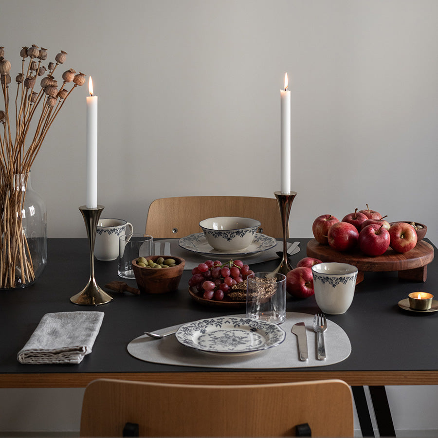 Stilig dekket bord med Seasons Fall Collection kopp, blå blomsterprint, arrangert med levende lys, frukt og tallerkener for en koselig middag.