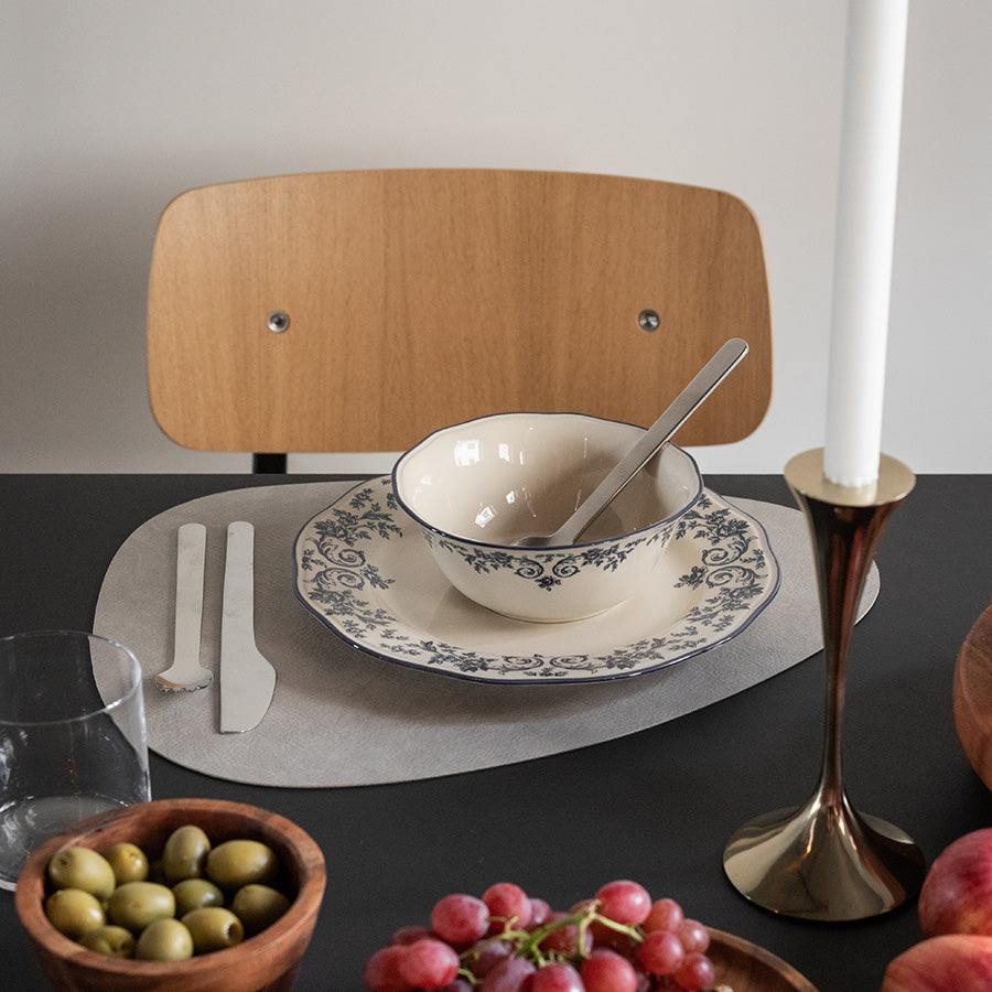 Elegant smaragdgrønn skål fra Seasons Fall Collection, dekket med blå blomsterprint, plassert på et bord med bestikk og moderne stoler.