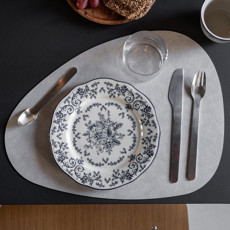 Seasons tallerken med blå blomsterdekor, perfekt tilborddekkingen, plassert på et stilig spisebord med bestikk og glass.
