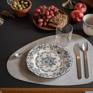 Tallerken fra Seasons med blå blomstermønster, servert med druer og kjeks på et elegant dekket bord.
