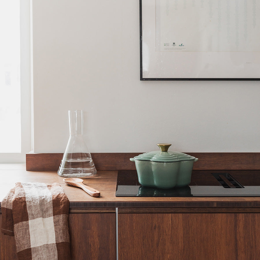 Seasons Easter Collection Støpejernsgryte Blomst 1,9L 30cm Grønn plassert på en moderne kjøkkenbenk, illustrerer allsidigheten og stilrenheten til støpejernsgryten.