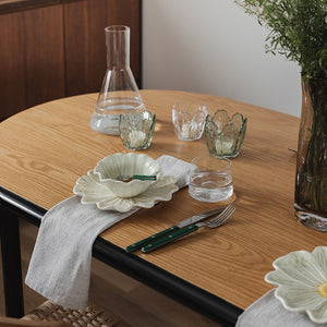 Detalj av Seasons lyslykter i klar glass, 8,5x8 cm, plassert ved siden av tallerkener og glass for en estetisk borddekorasjon.