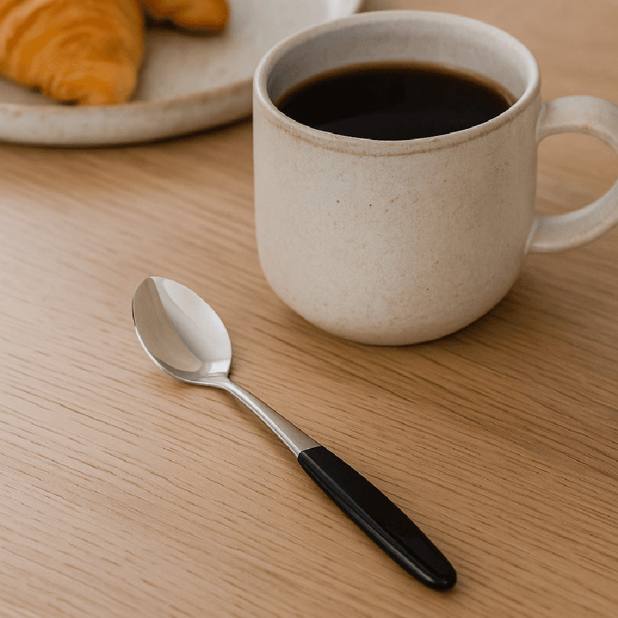 SKAUGUM – Skaugum Bestikk Sort Kaffeskje brukt ved kaffekopp på trebord, elegant sort skaft for kaffepause