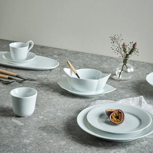 SKAUGUM Skaugum Bestikk Dessertskje Fjord – Dessertskje i fjord-seriens stil, vist på borddekking med porselen og trebestikk (Dessertskje ).