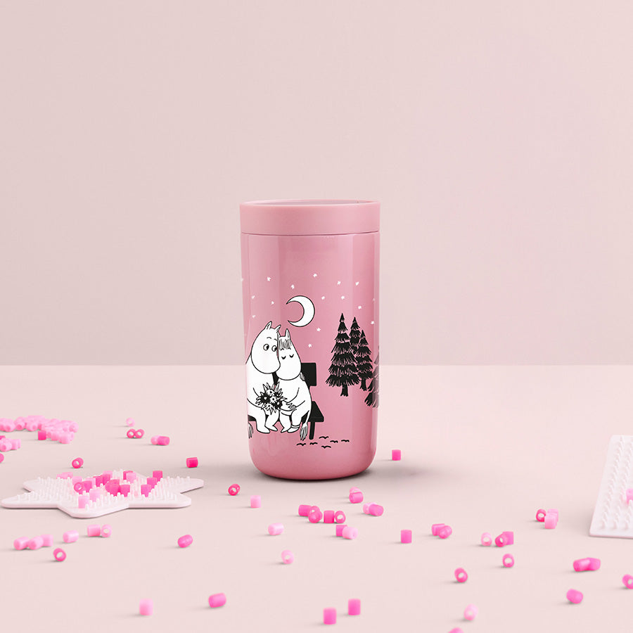 Elegant Stelton termokopp I LOVE YOU i rosa, med Mummi-kunstverk og dekorative elementer i rosa på bordet.